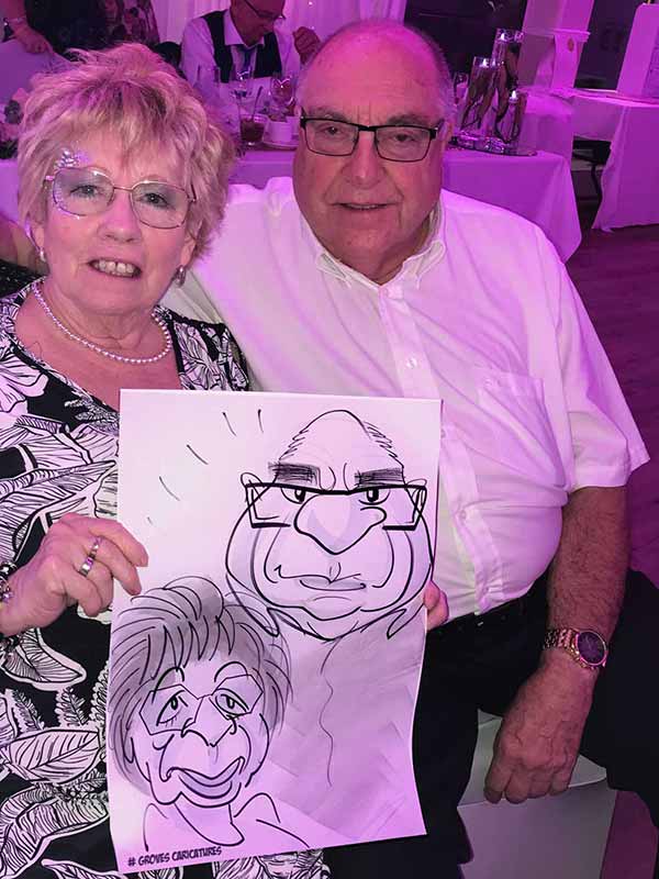 portsmouth couple hold their caricature up and smile